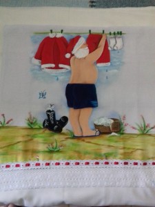 Pano de Prato com pintura do Papai Noel lavando roupa e bico com renda.